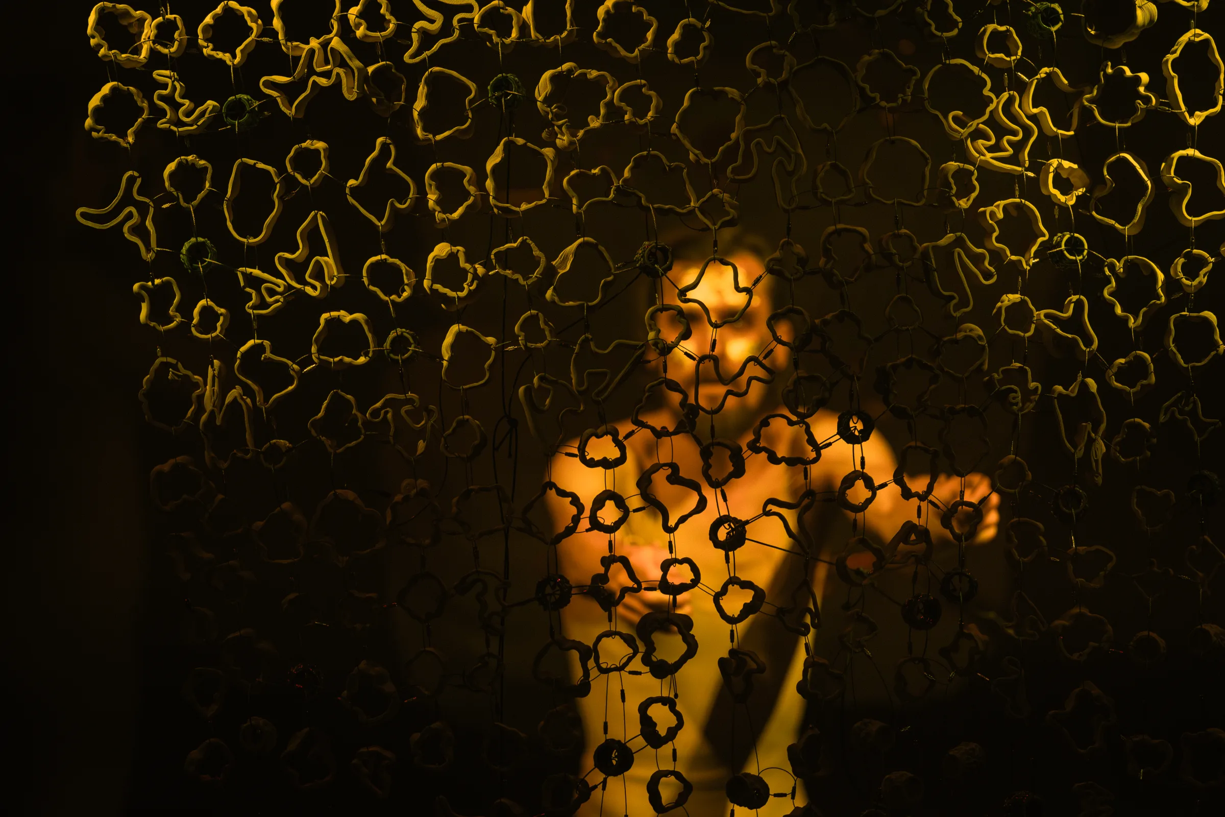 A performer carries a ceramic form through an orange projected landscape.