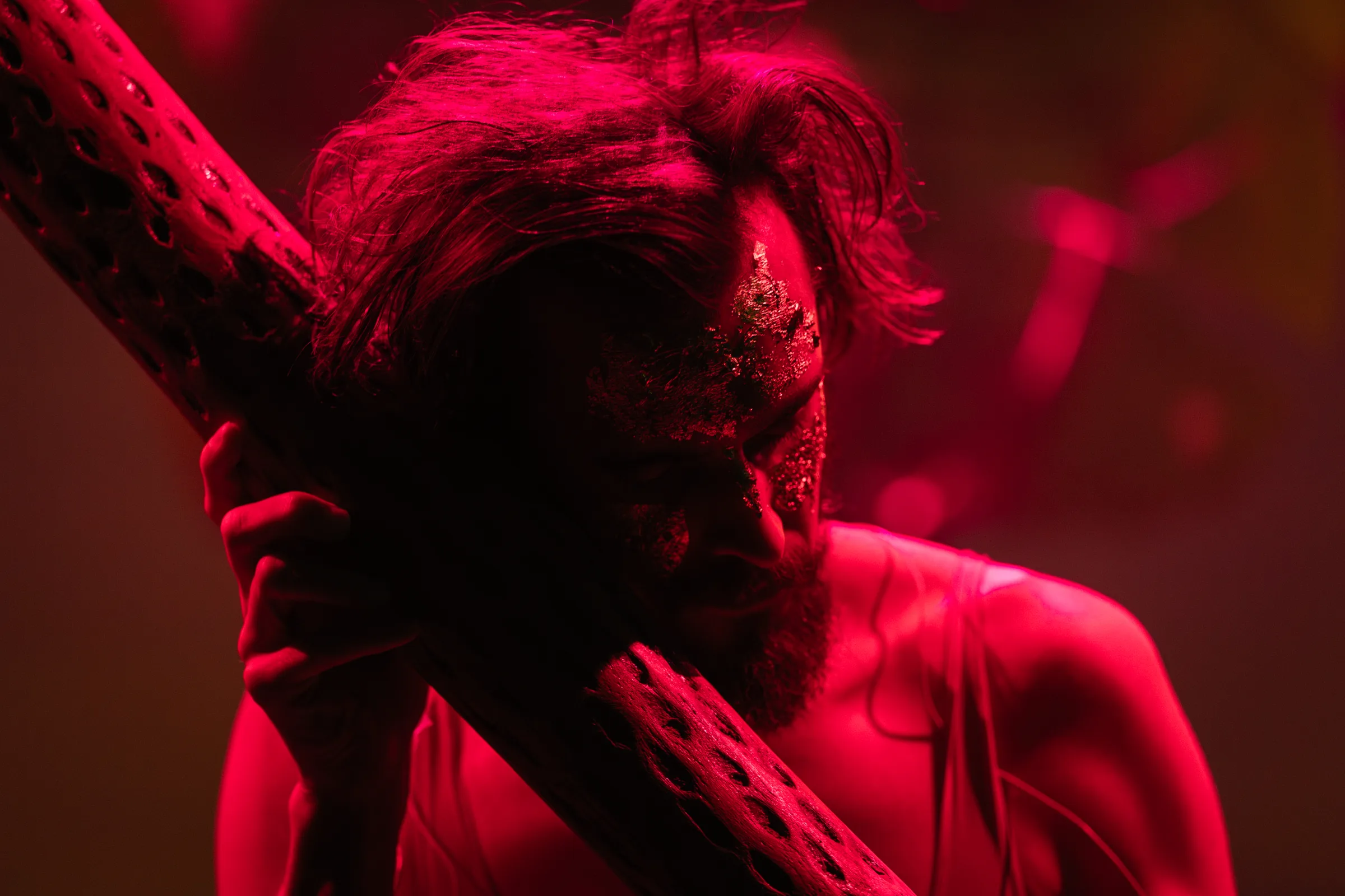 A performer holds a textured ceramic instrument in red light.